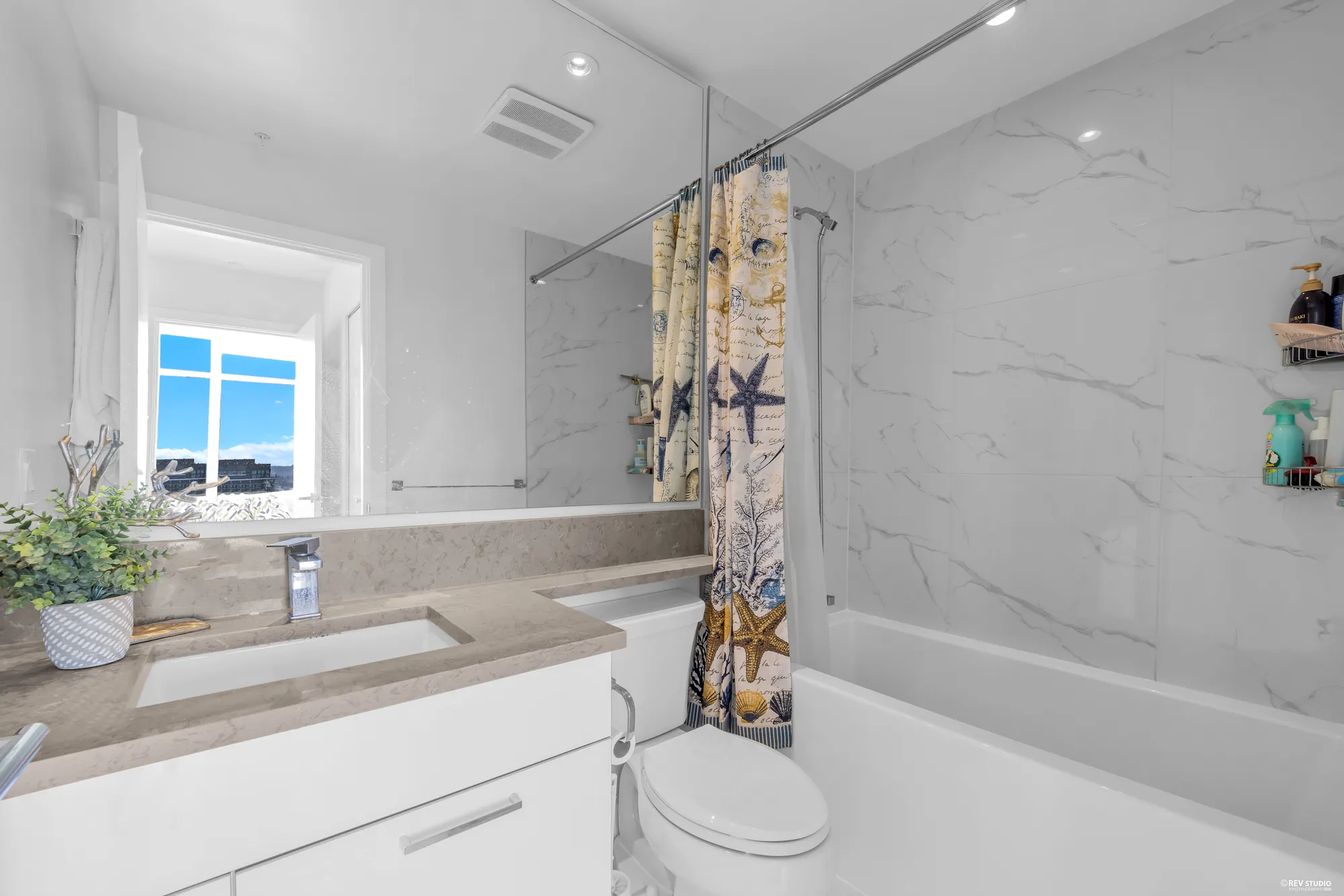 The three-piece bathroom with a tub, a glass screen and a marble-look surround