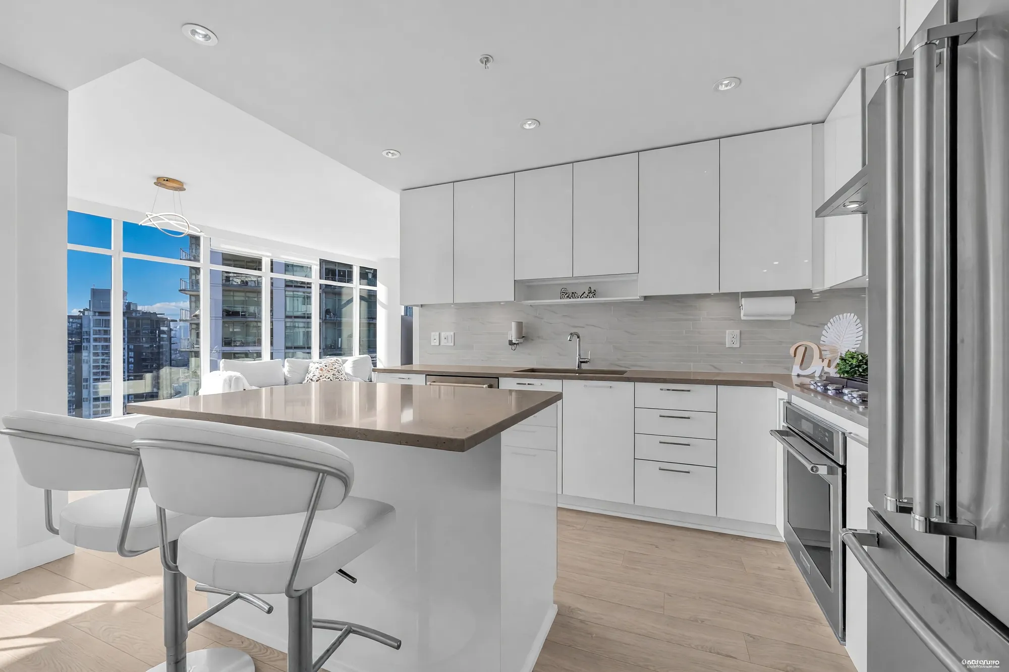 The kitchen island and bar stools with the window seat beyond, photographed after clutter was digitally removed