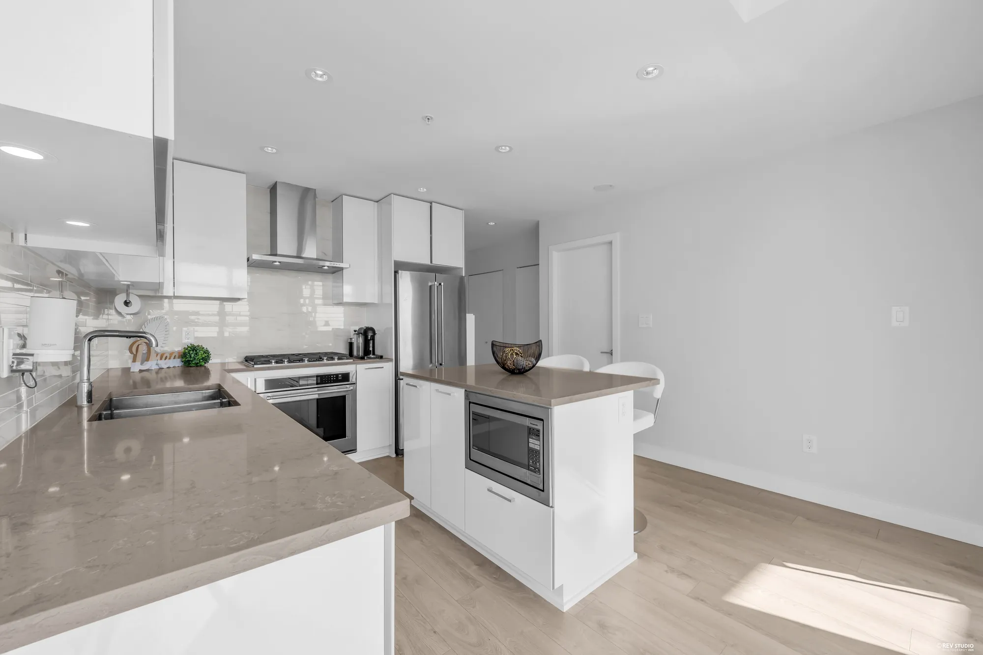The kitchen with a quartz island, integrated cabinetry and a gas cooktop