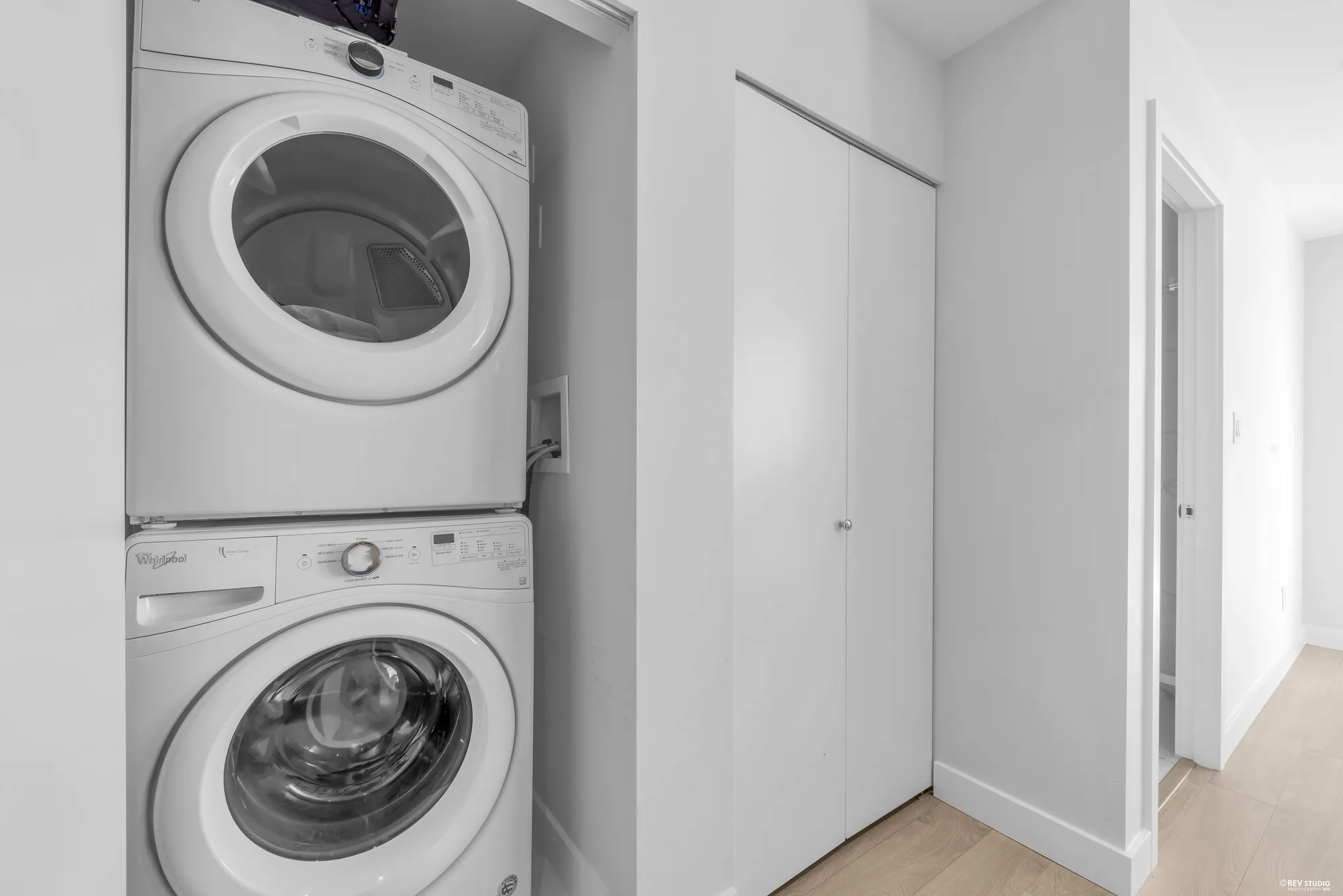 A stacked washer and dryer in a closet off the hall