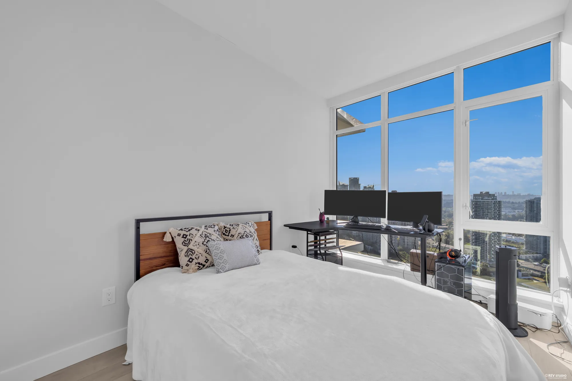The primary bedroom with the bed against the glass and the city beyond